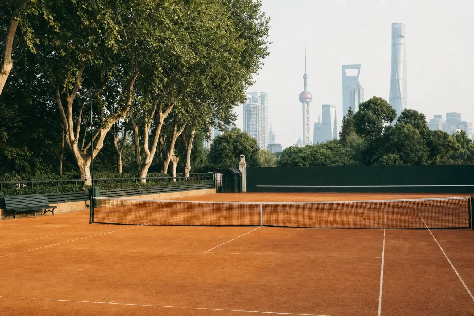A clay court at a Shanghai club under plane trees, the skyline fading into haze beyond.
